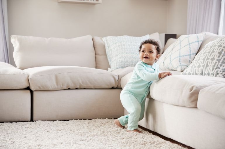 bébé debout se tient au canapé